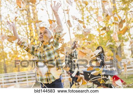 Stock Image - Boy playing in autumn leaves. Fotosearch