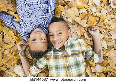 Brothers laying together in autumn leaves View Large Photo Image Stock Photo - Brothers laying together in autumn leaves. Fotosearch