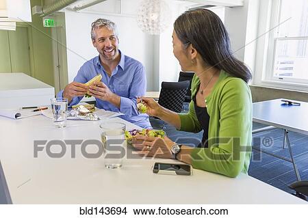 Picture - Business people having lunch together in office. Fotosearch