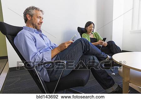 Stock Image - Business people using cell phones in office. Fotosearch