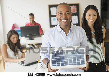 Stock Photo - Businessman holding solar panel model in office. Fotosearch