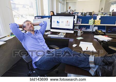 Stock Photo - Businessman relaxing at desk in office. Fotosearch