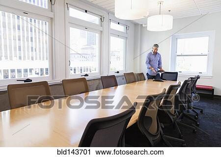 Stock Image - Businessman standing at table in conference room. Fotosearch