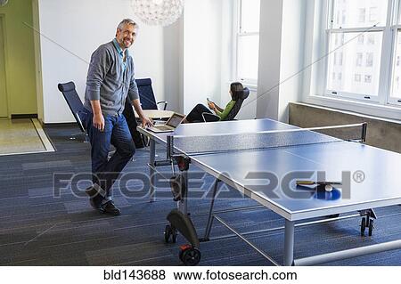 Businessman standing at table tennis table in office View Large Photo Image Stock Photo - Businessman standing at table tennis table in office. Fotosearch
