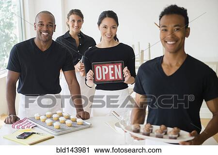 Caterers smiling together with food and open sign in event space View Large Photo Image Stock Image - Caterers smiling together with food and open sign in event space. Fotosearch