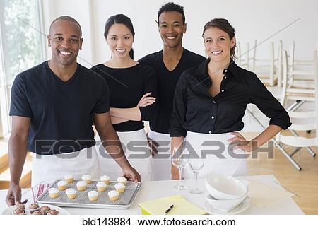 Picture - Caterers smiling with food in event space. Fotosearch