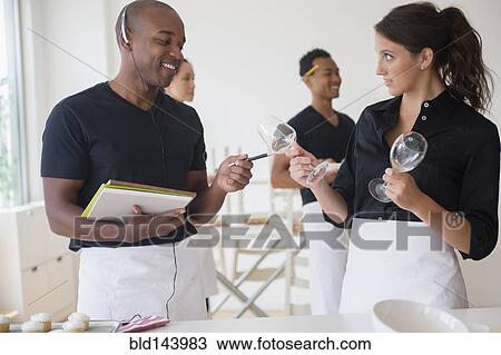 Stock Image - Caterers working together in event space. Fotosearch