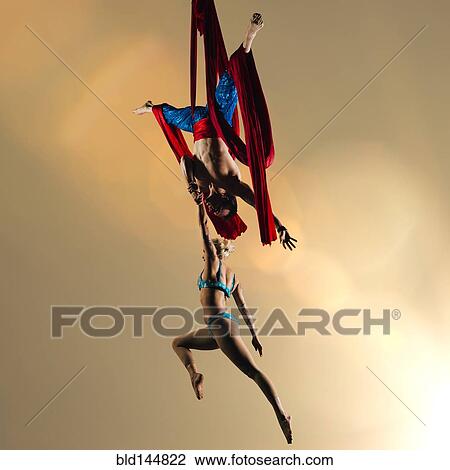 Stock Image - Caucasian acrobats performing with silk ropes. Fotosearch