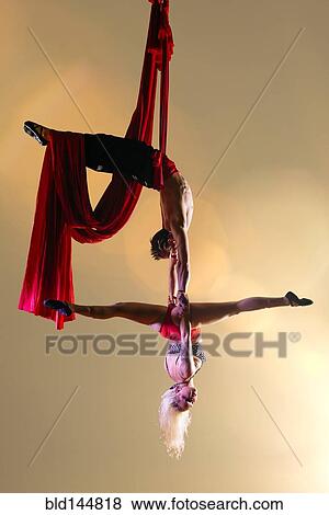 Stock Photo - Caucasian acrobats performing with silk ropes. Fotosearch