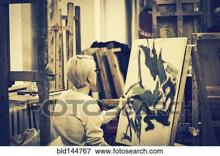 Stock Photo - Caucasian artist painting on canvas in studio. Fotosearch