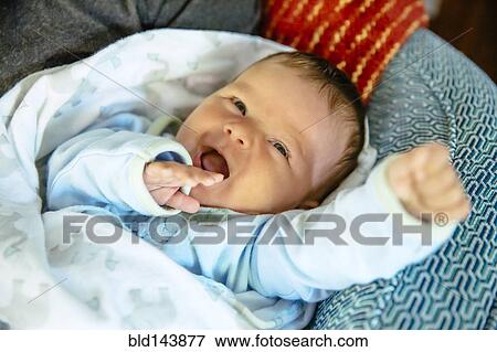 Stock Photo - Caucasian baby boy laughing on sofa. Fotosearch