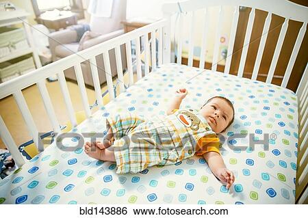 Stock Photograph - Caucasian baby boy laying in crib. Fotosearch