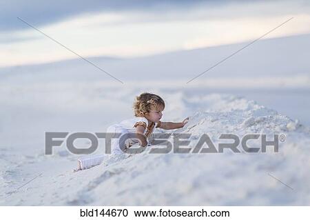 Stock Image - Caucasian boy climbing sand dune. Fotosearch