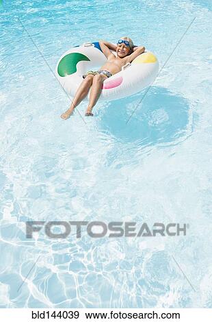 Stock Photo - Caucasian boy floating in inflatable ring in swimming pool. Fotosearch