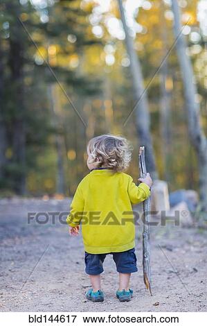 Stock Photo - Caucasian boy hiking on dirt path in forest. Fotosearch