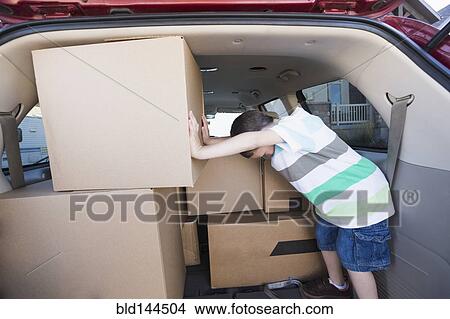 Caucasian boy packing cardboard boxes in car View Large Photo Image Picture - Caucasian boy packing cardboard boxes in car. Fotosearch