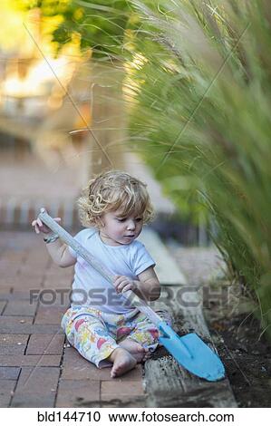 Caucasian boy playing with spade in garden View Large Photo Image Stock Image - Caucasian boy playing with spade in garden. Fotosearch