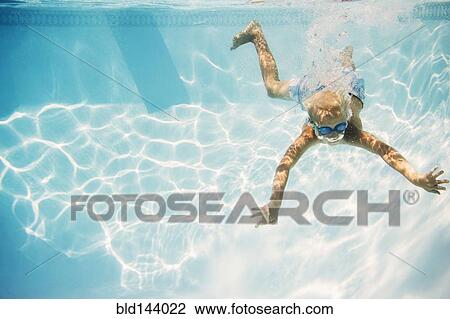 Stock Image - Caucasian boy swimming underwater in pool. Fotosearch