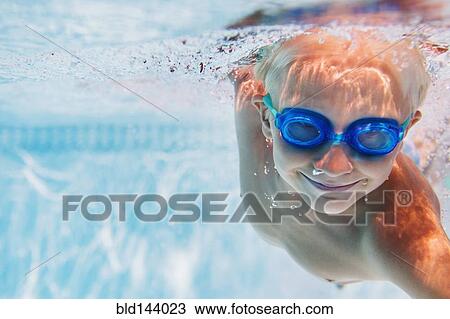 Stock Image - Caucasian boy swimming underwater in pool. Fotosearch