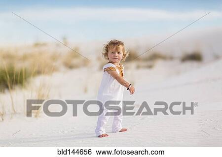Stock Photograph - Caucasian boy walking on sand dune. Fotosearch