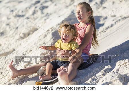 Caucasian brother and sister sledding on sand dune View Large Photo Image Stock Image - Caucasian brother and sister sledding on sand dune. Fotosearch
