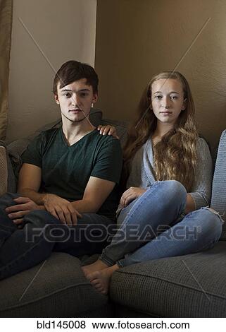 Stock Photo - Caucasian brother and sister smiling on sofa. Fotosearch