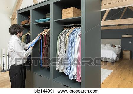 Stock Image - Caucasian businessman dressing in bedroom. Fotosearch