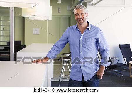 Stock Image - Caucasian businessman smiling in office. Fotosearch