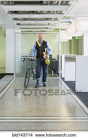 Caucasian businessman with bicycle in office View Large Photo Image Picture - Caucasian businessman with bicycle in office. Fotosearch