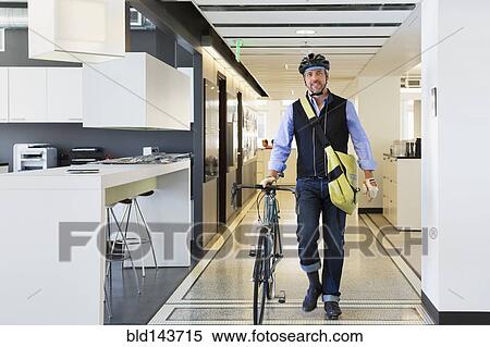 Stock Photography - Caucasian businessman with bicycle in office. Fotosearch