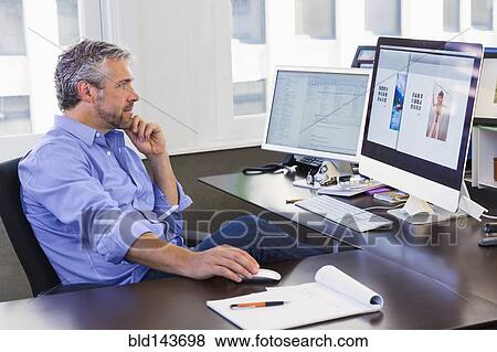 Stock Photo - Caucasian businessman working at computer in office. Fotosearch