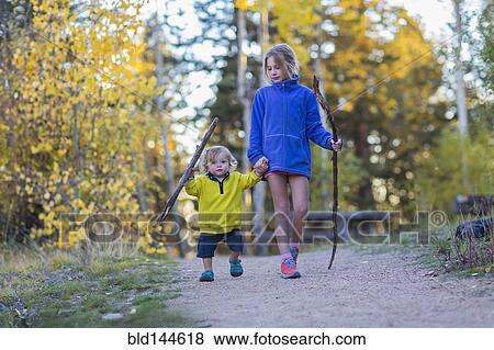 Stock Photo - Caucasian children hiking on dirt path in forest. Fotosearch