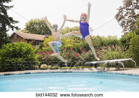 Stock Image - Caucasian children jumping into swimming pool. Fotosearch