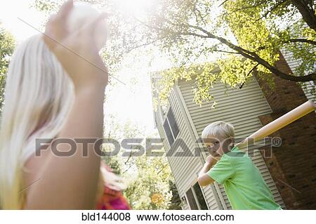Stock Photo - Caucasian children playing baseball in backyard. Fotosearch