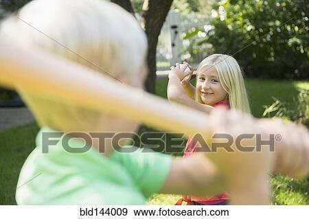 Stock Photo - Caucasian children playing baseball in backyard. Fotosearch
