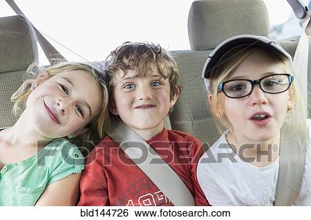 Stock Photograph - Caucasian children smiling in back seat of car. Fotosearch