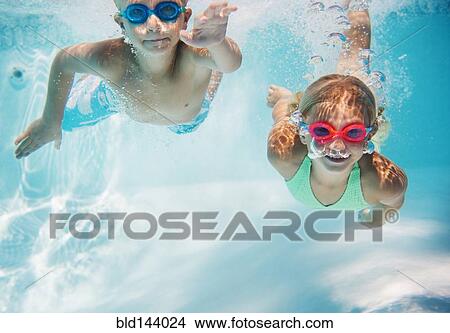 Picture - Caucasian children swimming underwater in pool. Fotosearch