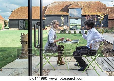 Stock Image - Caucasian couple eating lunch in backyard. Fotosearch