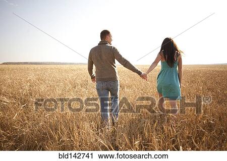 Caucasian couple holding hands in rural field View Large Photo Image Stock Image - Caucasian couple holding hands in rural field. Fotosearch