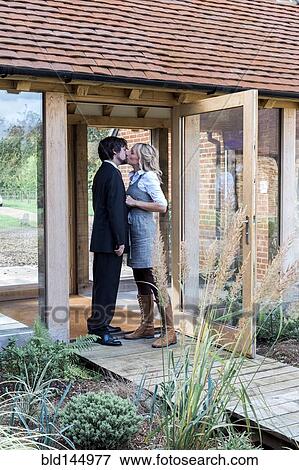 Stock Photo - Caucasian couple kissing at front door. Fotosearch