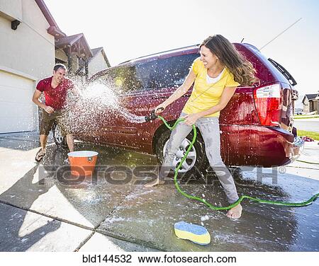 Caucasian couple playing while washing car in driveway View Large Photo Image Stock Image - Caucasian couple playing while washing car in driveway. Fotosearch