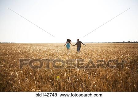 Stock Photo - Caucasian couple running in rural field. Fotosearch