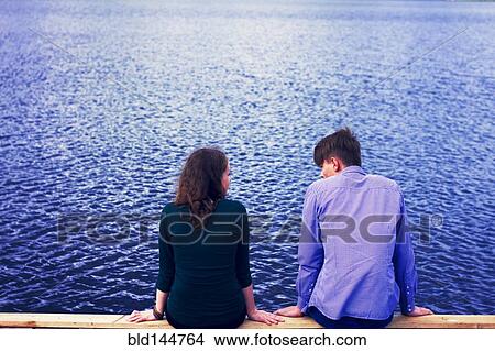 Picture - Caucasian couple sitting on dock at lake. Fotosearch