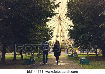 Stock Image - Caucasian couple walking on path in park. Fotosearch