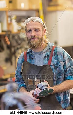 Stock Photograph - Caucasian craftsman smiling in workshop. Fotosearch