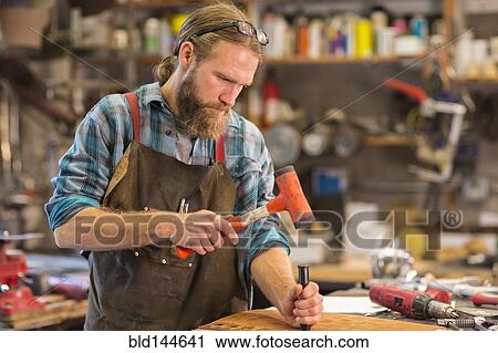 Stock Image - Caucasian craftsman working in workshop. Fotosearch