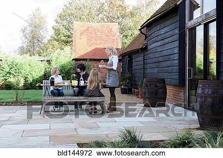 Stock Image - Caucasian family eating breakfast in backyard. Fotosearch