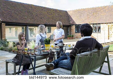Stock Image - Caucasian family eating breakfast in backyard. Fotosearch