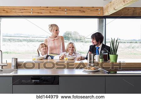 Stock Photo - Caucasian family eating breakfast in kitchen. Fotosearch