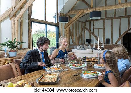 Picture - Caucasian family eating dinner in dining room. Fotosearch